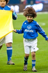A child wearing an Allstate Insurance jersey helps carry a flag onto the field at a Mexican National Futbol Team match