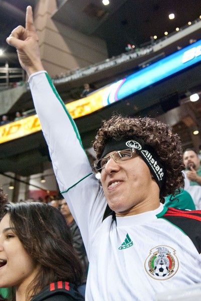 A fan stands to support the Mexico Men's National Futbol Team in Houston in 2012, sporting a wig gotten from Allstate in their fan village.  Event Photography by Ari Shapiro - AShapiroStudios.com