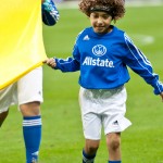 A child wearing an Allstate Insurance jersey helps carry a flag onto the field at a Mexican National Futbol Team match